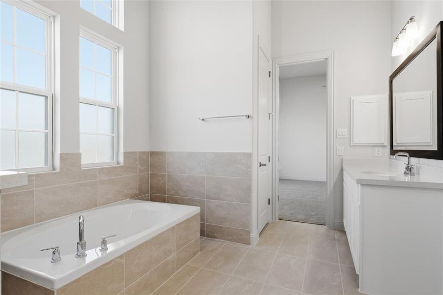 Full bathroom with vanity, a garden tub, and light tile patterned floors