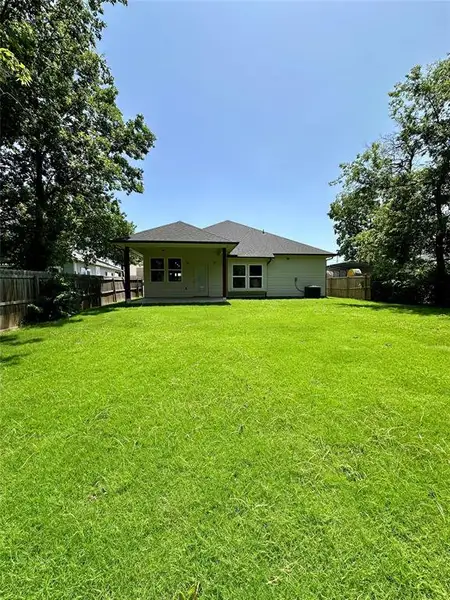 Spacious backyard with a lush green lawn, private fencing, and mature perimeter trees Spacious backyard with a lush green lawn, private fencing, and mature perimeter trees