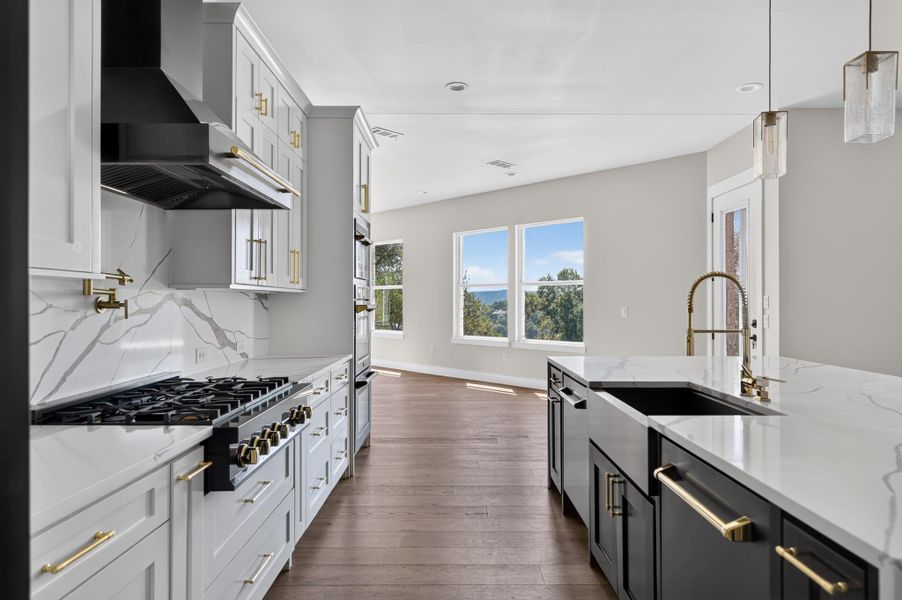 Rich hardwood floors flow past a central stone island toward a bright adjoining living area.