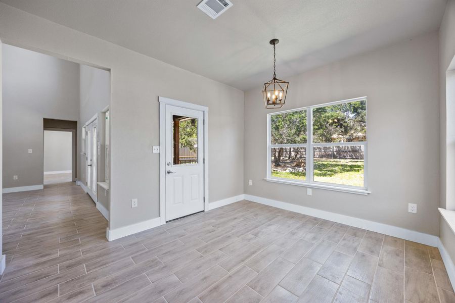 Spare room with baseboards, light wood-style floors, a notable chandelier, and visible vents Spare room with baseboards, light wood-style floors, a notable chandelier, and visible vents