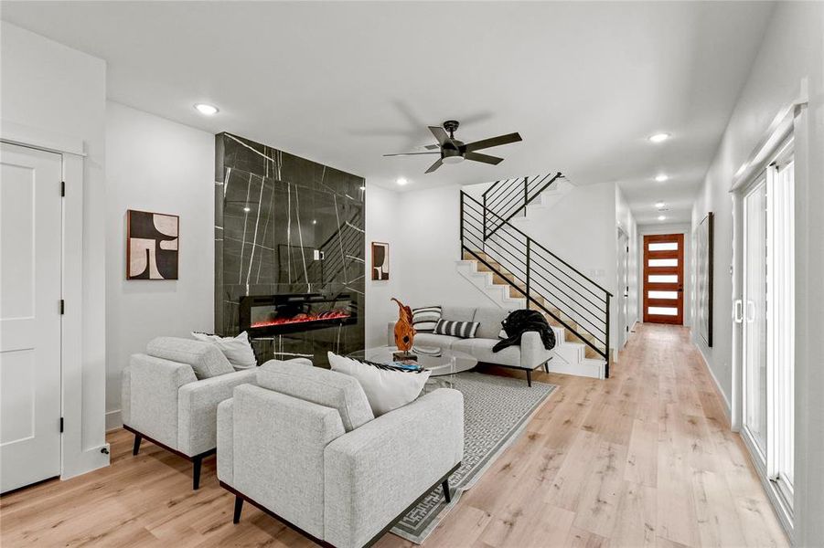 Living room with ceiling fan, light hardwood / wood-style floors, and a tiled fireplace