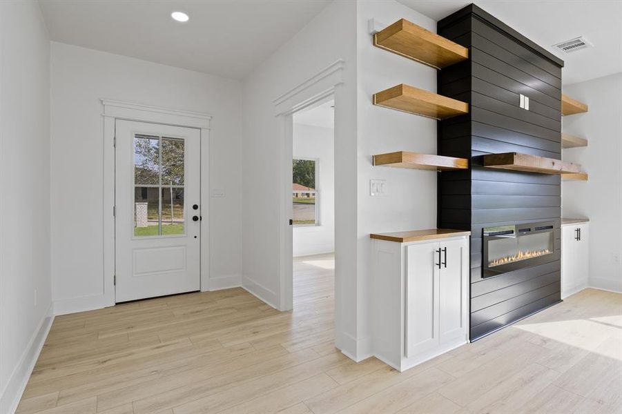Doorway to outside with a large fireplace, wood finished floors, and recessed lighting