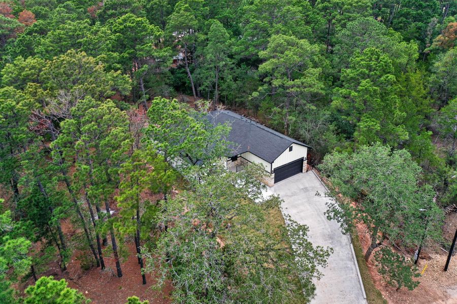 Single-story residence featuring a dark shingle roof, light-colored siding, and a dark garage door Single-story residence featuring a dark shingle roof, light-colored siding, and a dark garage door