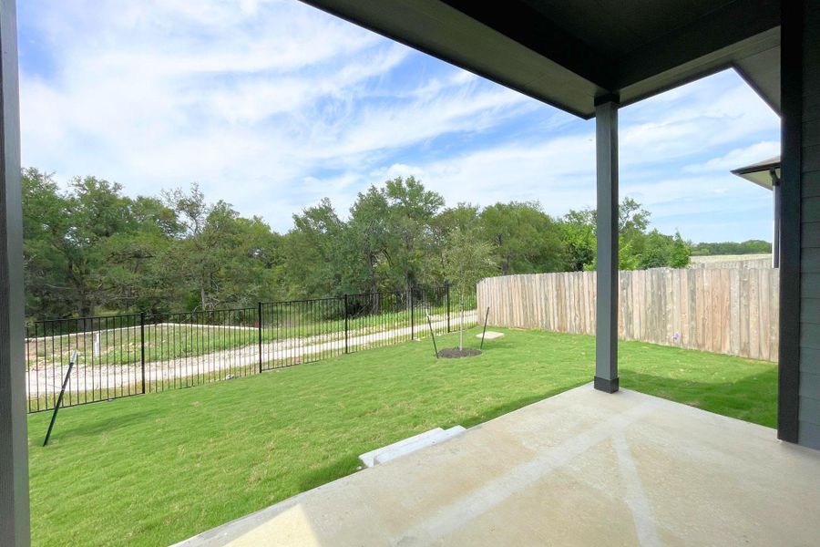 A spacious backyard with fresh green lawn and a generous concrete patio, ideal for outdoor leisure.
