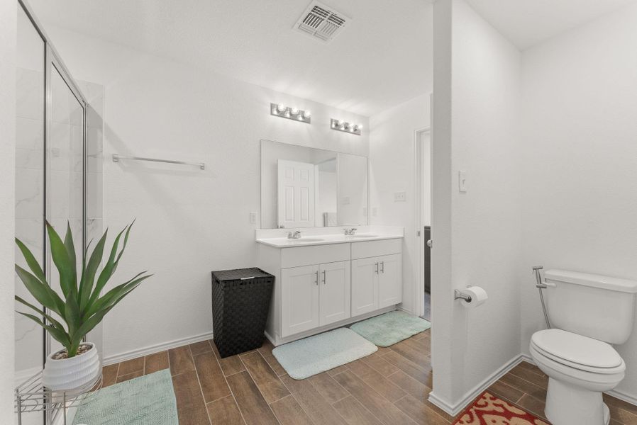 Bathroom with double vanity, visible vents, wood tiled floor, a sink, and baseboards