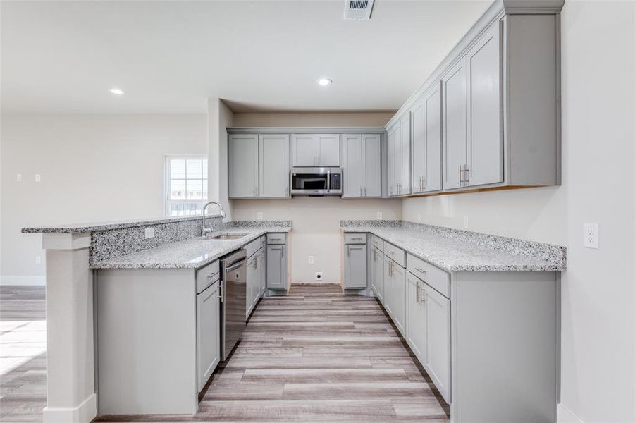 Similar home: Kitchen featuring gray cabinets, sink, stainless steel appliances, and wood-style flooring.