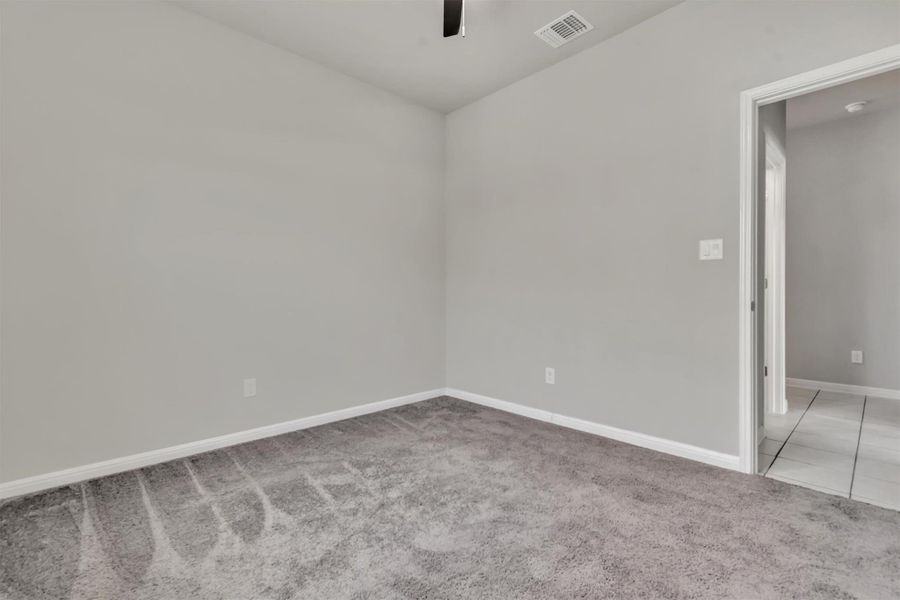 An inviting room features plush carpet and an open doorway leading to tiled flooring.