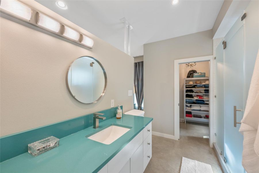 A well-lit primary bathroom features a vibrant countertop and a spacious walk-in closet. A well-lit primary bathroom features a vibrant countertop and a spacious walk-in closet.