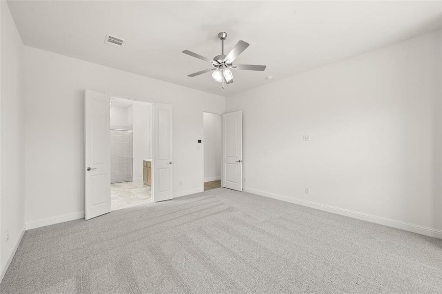 Unfurnished bedroom with light colored carpet, connected bathroom, and a ceiling fan