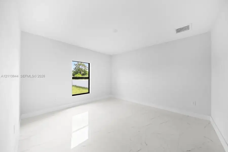 Neutral interior space featuring polished tile flooring with a veined pattern, stark white walls, and a single-pane window with a black frame Neutral interior space featuring polished tile flooring with a veined pattern, stark white walls, and a single-pane window with a black frame