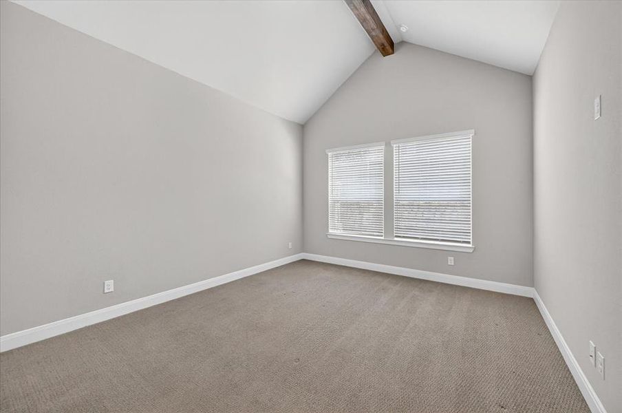 Vaulted ceiling with an exposed wood beam, two windows with blinds, light gray wall paint, white trim, and neutral-toned carpet flooring Vaulted ceiling with an exposed wood beam, two windows with blinds, light gray wall paint, white trim, and neutral-toned carpet flooring