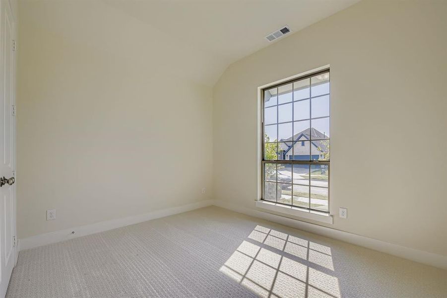 Empty room with light carpet and vaulted ceiling