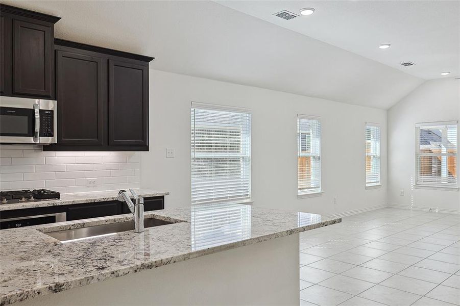 Kitchen featuring appliances with stainless steel finishes, a healthy amount of sunlight, vaulted ceiling, and sink