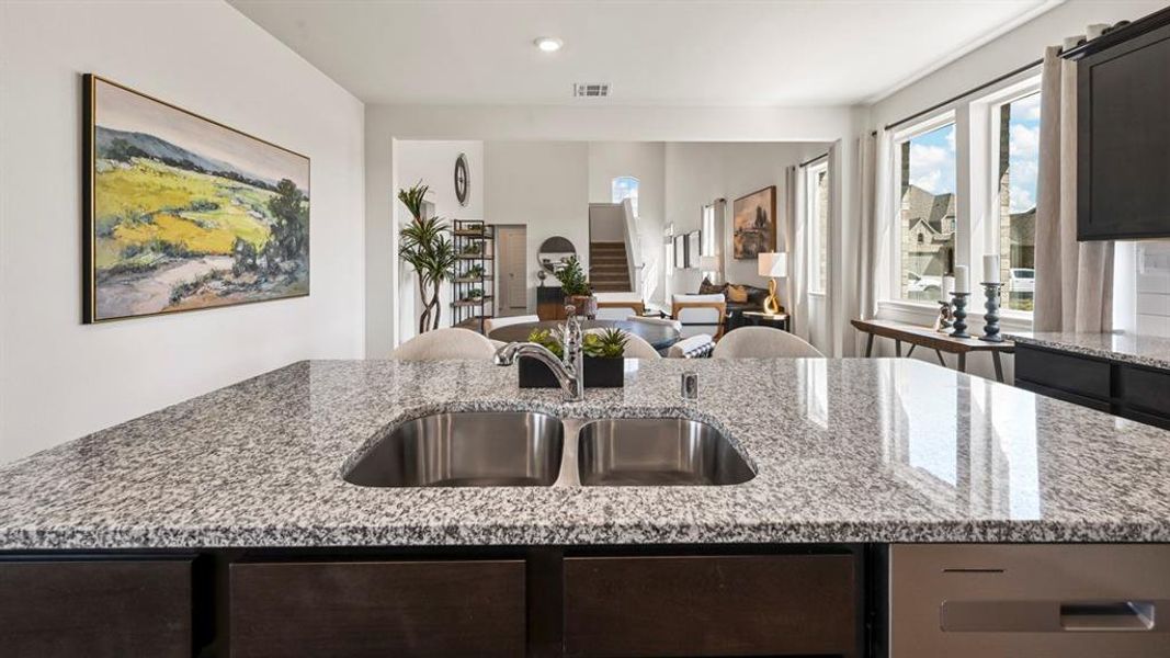 Kitchen with light stone counters, open floor plan, a center island with sink, recessed lighting, and dark cabinets Kitchen with light stone counters, open floor plan, a center island with sink, recessed lighting, and dark cabinets