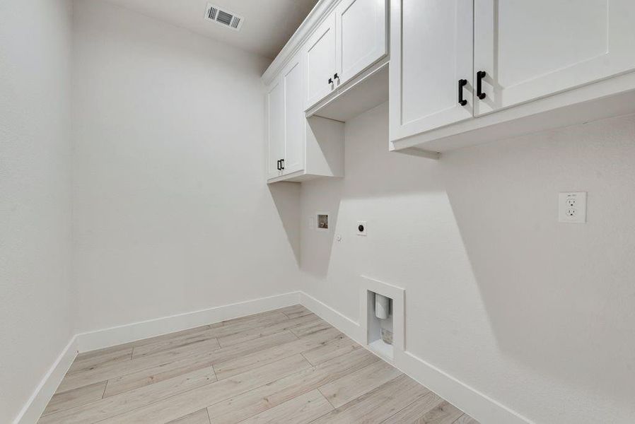 Laundry room with light wood-style flooring, cabinet space, electric dryer hookup, and washer hookup