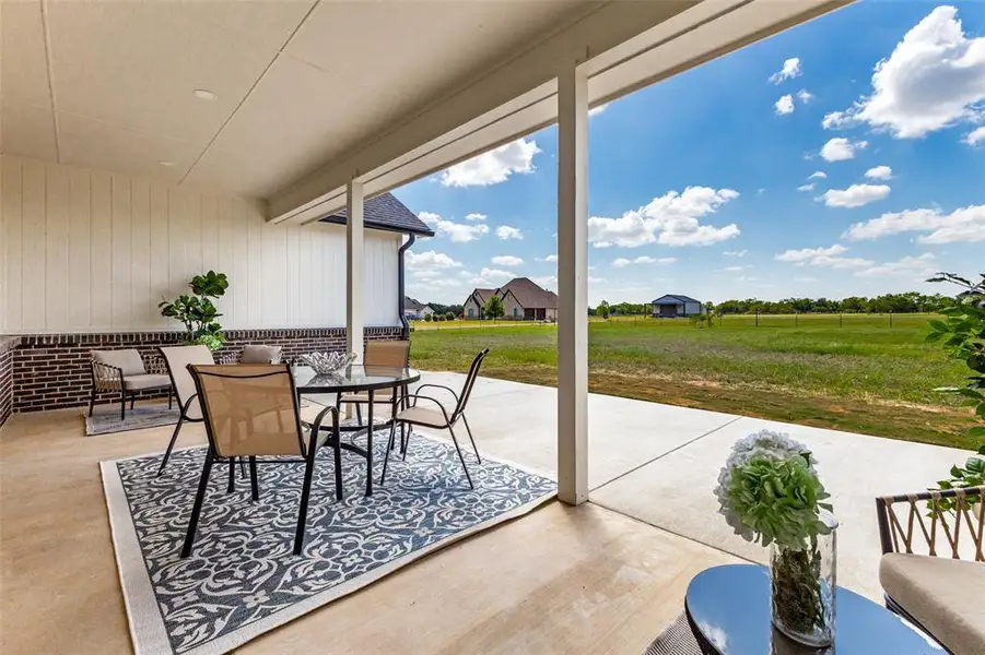 Covered patio with a concrete surface, brick wainscoting, and white vertical siding
