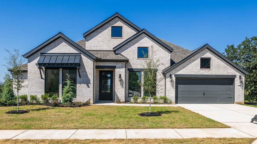 View of front of house featuring brick siding, a front yard, a standing seam roof, and concrete driveway View of front of house featuring brick siding, a front yard, a standing seam roof, and concrete driveway