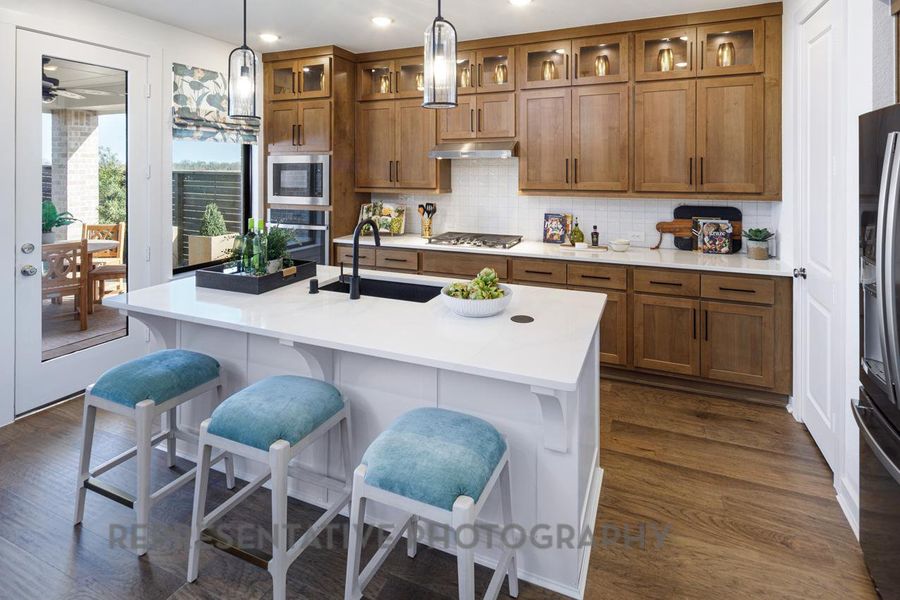 Kitchen with appliances with stainless steel finishes, brown cabinets, under cabinet range hood, decorative backsplash, and recessed lighting