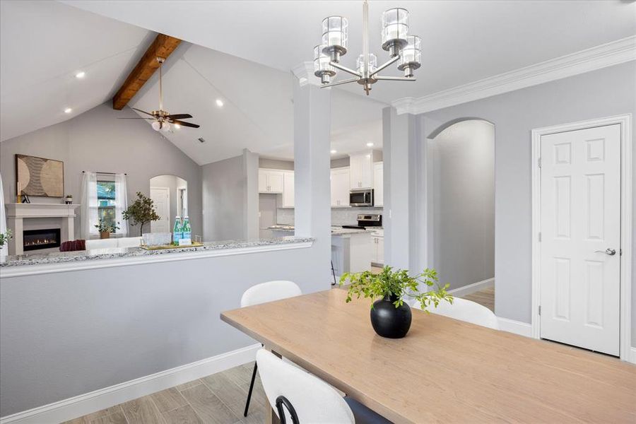 Dining room featuring ceiling fan with notable chandelier, crown molding, and vaulted ceiling with beams