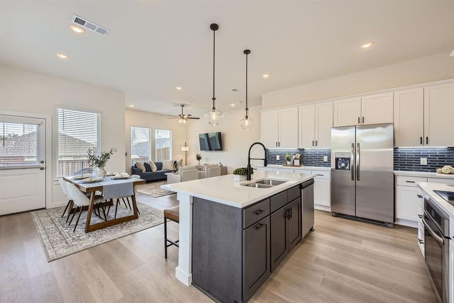 Kitchen featuring white cabinetry, hanging light fixtures, stainless steel appliances, decorative backsplash, and recessed lighting