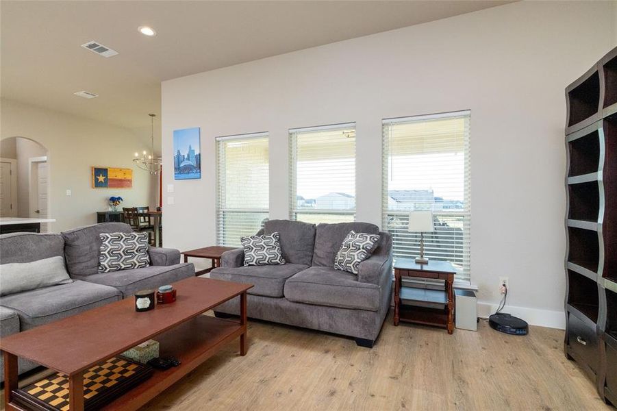 Living area featuring light wood-type flooring, arched walkways, a chandelier, and recessed lighting
