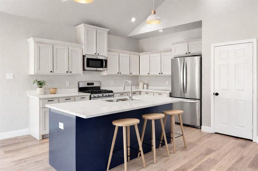 Kitchen featuring stainless steel appliances, a kitchen bar, white cabinetry, vaulted ceiling, and an island with sink Kitchen featuring stainless steel appliances, a kitchen bar, white cabinetry, vaulted ceiling, and an island with sink