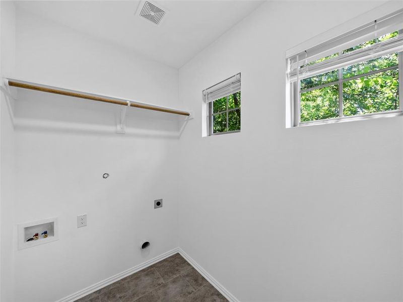 Laundry room featuring hookup for a washing machine, dark tile patterned floors, plenty of natural light, and electric dryer hookup