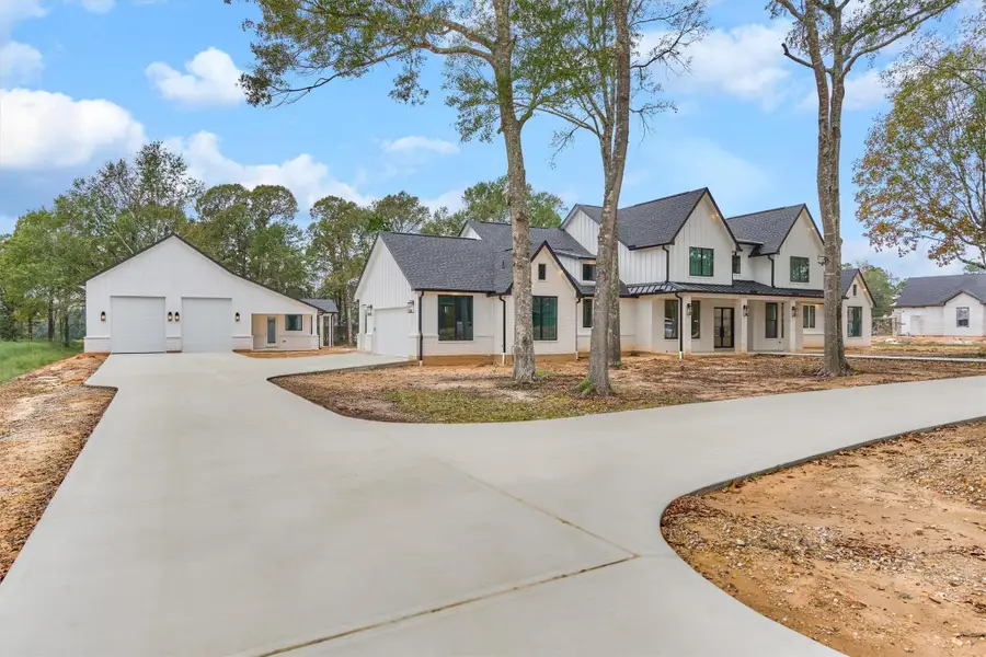Expansive circular drive leading to a modern farmhouse residence and oversized detached garage, all set on a peaceful, tree-lined property
