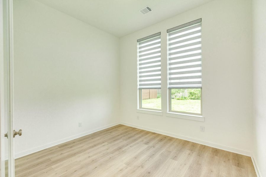 Spacious home office featuring dual windows that flood the room with natural light, creating an inviting and productive work area, or a peaceful, quiet retreat for focused tasks.