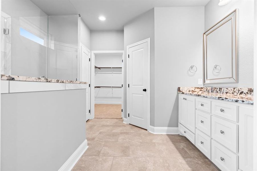 Master bathroom featuring walk in shower, vanity, and spacious walk-in closet Master bathroom featuring walk in shower, vanity, and spacious walk-in closet