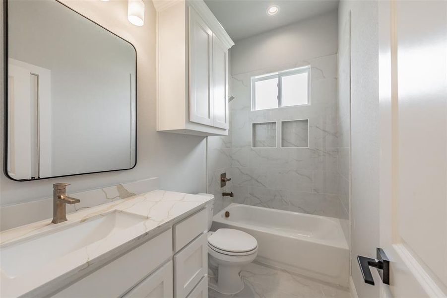 Guest bath features quartz countertops, an under mount sink, & a tiled shower tub combo.