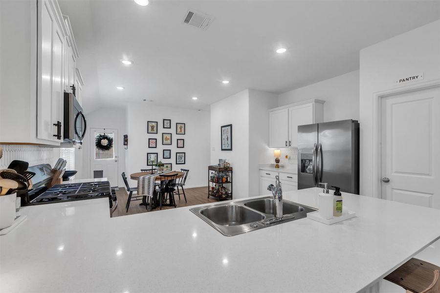 Here's a view of the large kitchen and dining area. This kitchen has a nice peninsula perfect for your cooking workspace and for multiple barstools. To the right is the large walk in pantry.