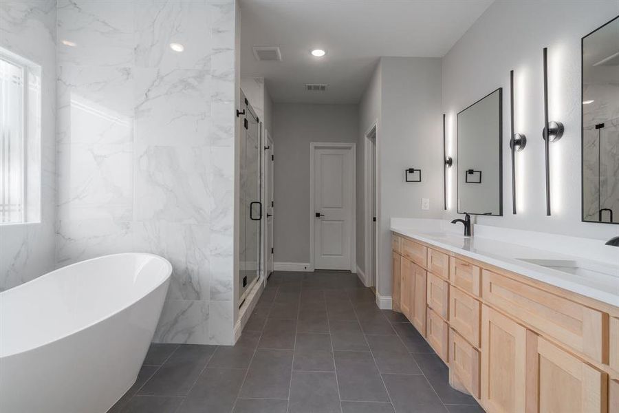 Bathroom featuring shower with separate bathtub, dual bowl vanity, tile flooring, and tile walls