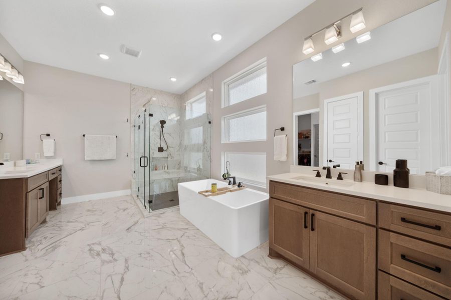 The primary bathroom offers a freestanding soaking tub perfectly positioned between the large walk-in shower and dual vanities, offering a relaxing focal point. The primary bathroom offers a freestanding soaking tub perfectly positioned between the large walk-in shower and dual vanities, offering a relaxing focal point.