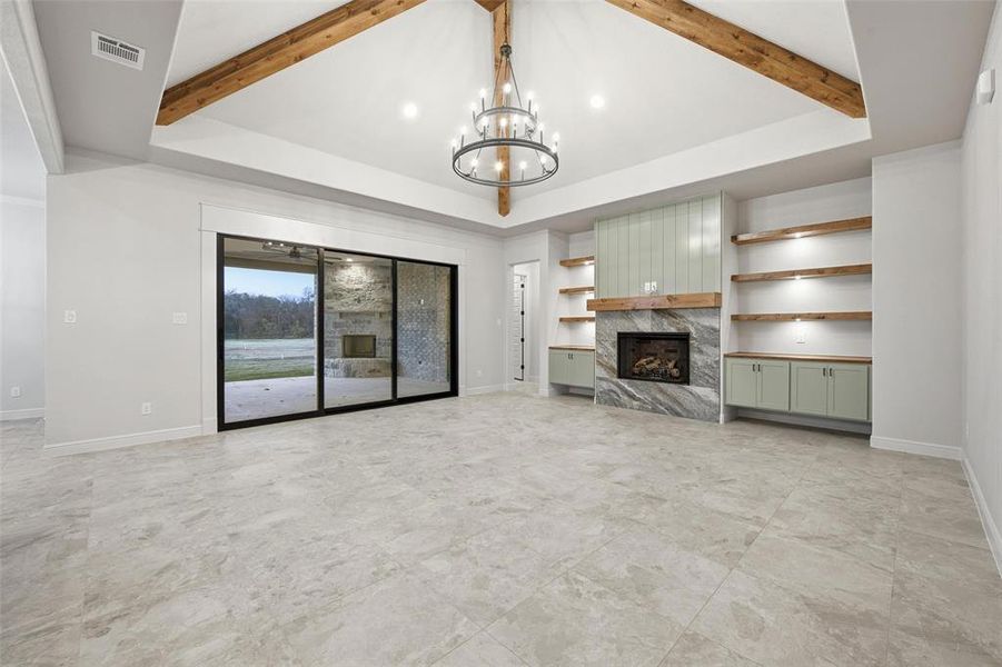 Unfurnished living room with a premium fireplace, a chandelier, and beam ceiling Unfurnished living room with a premium fireplace, a chandelier, and beam ceiling