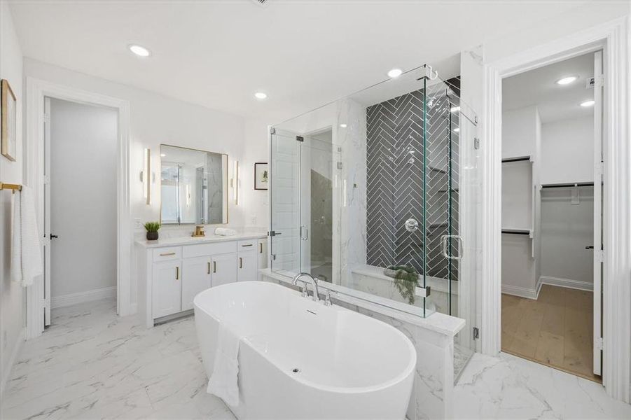 Freestanding soaking tub with a floor-mounted faucet, complemented by a glass-enclosed shower featuring herringbone tile and a built-in bench