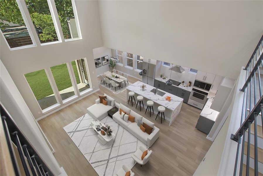 Living room with light hardwood / wood-style floors, a towering ceiling, and sink