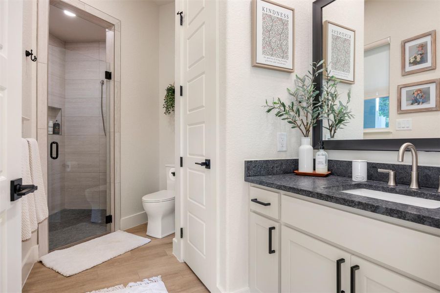 Bathroom featuring vanity, hardwood / wood-style floors, walk in shower, and toilet Bathroom featuring vanity, hardwood / wood-style floors, walk in shower, and toilet