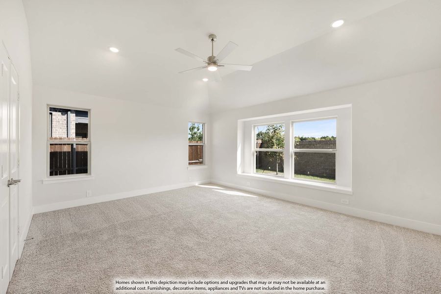 Empty bedroom with vaulted ceiling, ceiling fan, carpet flooring, and multiple windows with backyard views Empty bedroom with vaulted ceiling, ceiling fan, carpet flooring, and multiple windows with backyard views