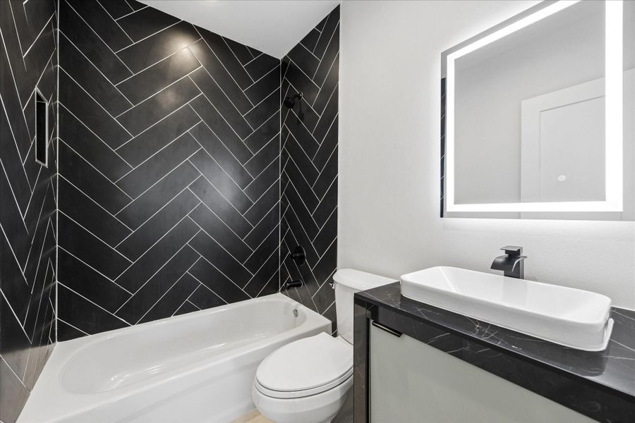 Stylish secondary bathroom featuring a striking floor-to-ceiling herringbone tile surround, sleek matte black fixtures, and a contemporary floating vanity. Stylish secondary bathroom featuring a striking floor-to-ceiling herringbone tile surround, sleek matte black fixtures, and a contemporary floating vanity.