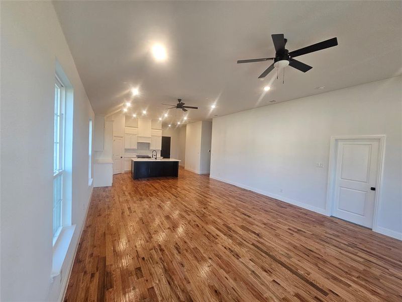 Unfurnished living room featuring hardwood / wood-style flooring, ceiling fan, and sink