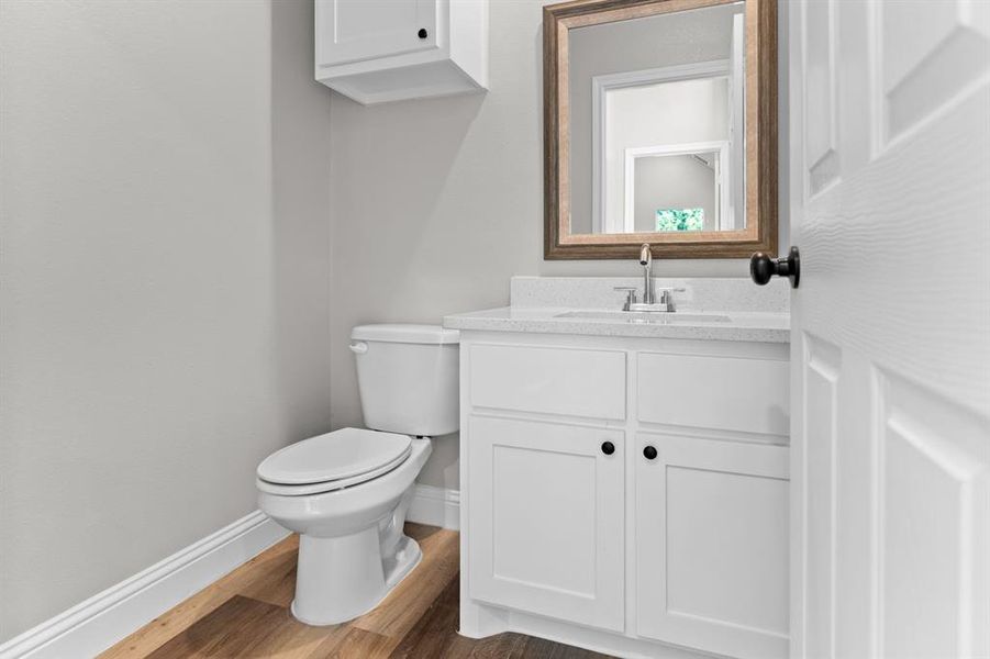 Bathroom with baseboards, vanity, toilet, and wood finished floors Bathroom with baseboards, vanity, toilet, and wood finished floors