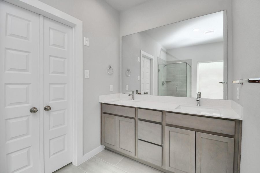 Elevate your daily routine at the elegant vanity, now equipped with double sinks, light countertops, modern hardware, and beautiful recessed lights. Sample photo of completed home with similar floor plan. Actual colors and selections may vary.