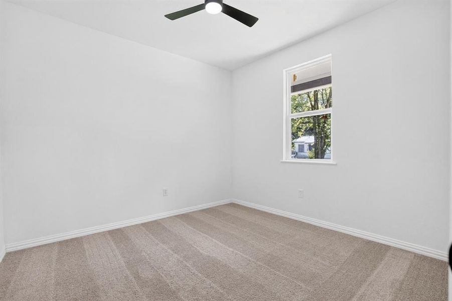 Neutral tone wall finishes, ceiling fan, natural light from a single window, baseboard trim, and neutral tone carpet flooring