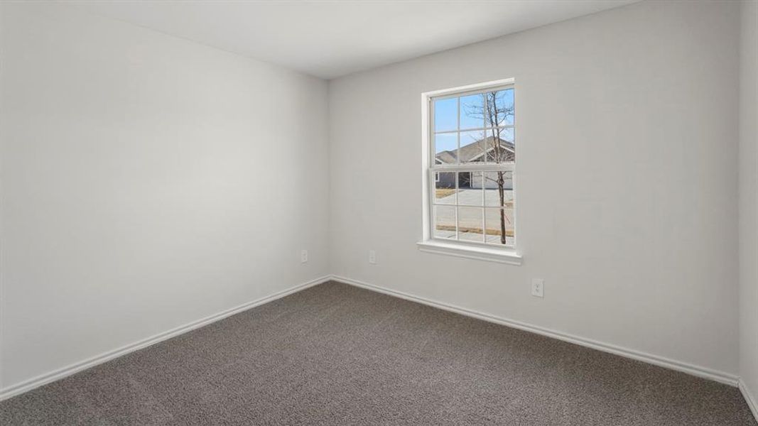 Neutral-toned room featuring a single window with grid panes, light gray carpeting, white baseboards, and white walls
