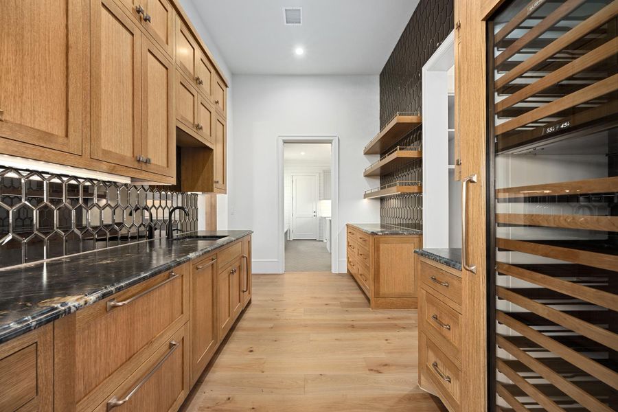 A well-appointed Butler's pantry with sink, SubZero wine cooler, refrigerator drawers, ice, and main pantry access.