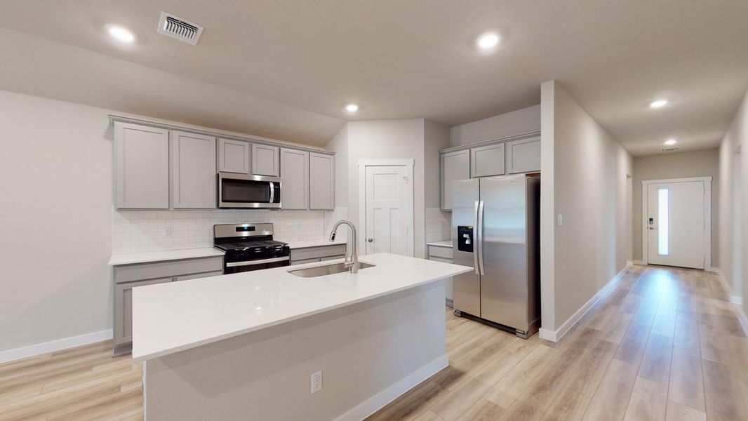 Kitchen featuring stainless steel appliances, light wood-type flooring, a kitchen island with sink, gray cabinetry, and recessed lighting