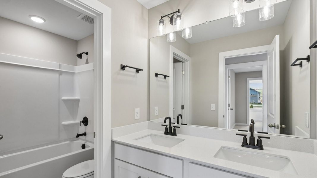Secondary bathroom with dual vanity and door to shower and toilet Secondary bathroom with dual vanity and door to shower and toilet