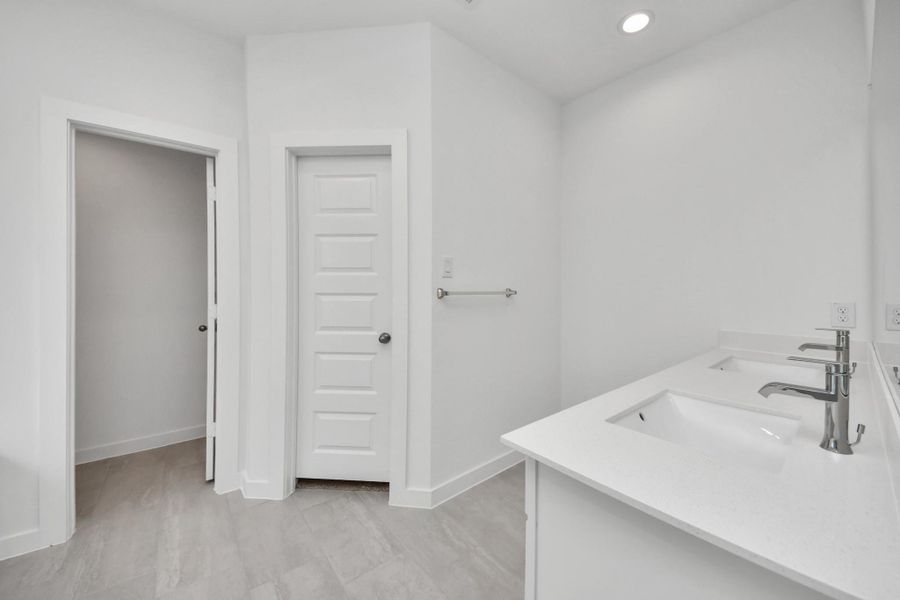 Escape to a spa-like oasis in this primary bathroom. Enjoy a walk-in shower with tile surround, a separate garden tub with custom detailing, and an elegant vanity featuring light countertops, modern hardware, and beautiful recessed lights. Experience luxury and relaxation in every detail. Sample photo of completed home with similar floor plan. Actual colors and selections may vary.