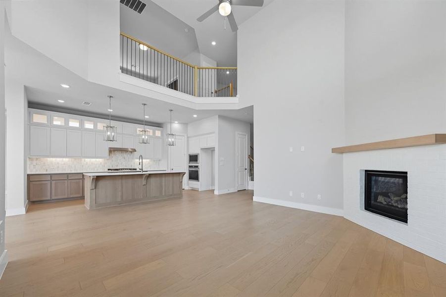 Unfurnished living room with high vaulted ceiling, light wood-style floors, recessed lighting, a brick fireplace, and ceiling fan
